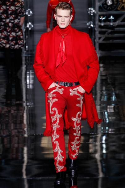 L&#39;uomo di Versace diventa un cowboy. Il cappotto  monocromatico, cos come i pantaloni in pelle con paracolpi in vista